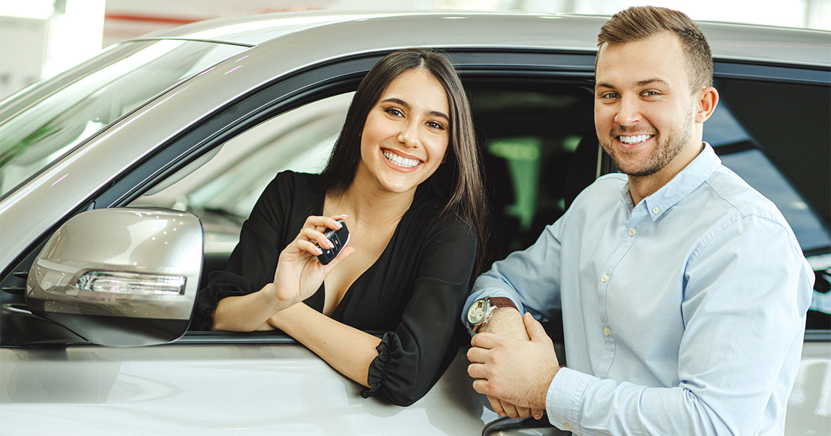 Woman getting her keys for her brand new car from a car salesman.